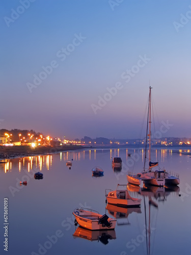 Seixal Bay with small boats and a sailing trimaran at twilight, nightfall, dusk or evening. Setubal, Portugal photo