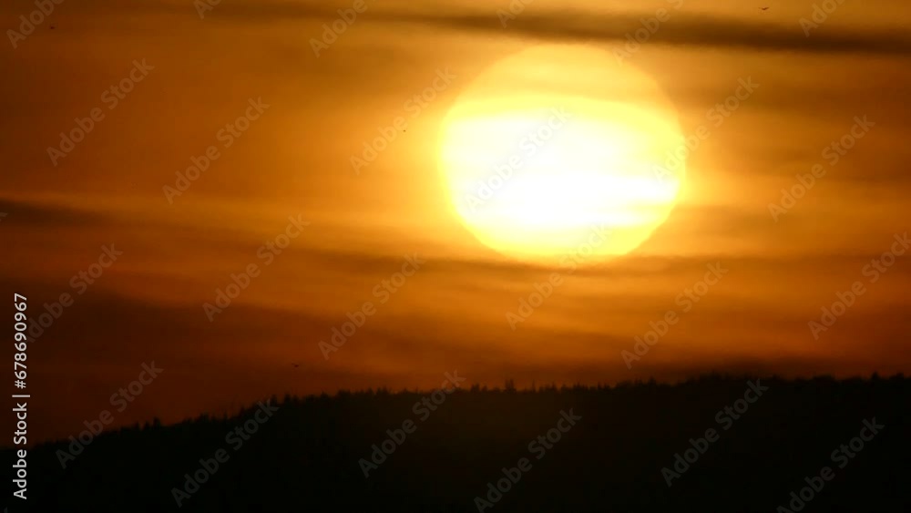Sky with orange clouds, yellow sun, dark horizon of forests in mountains and birds in flight during sunrise in autumn morning - real time. Sky with orange clouds, yellow sun, dark horizon of forests in mountains and birds in flight during sunrise in autumn morning - real time.