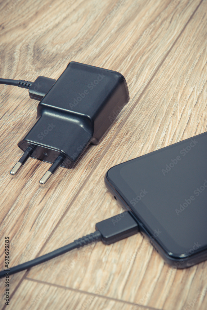 Black smartphone and charger using to charge empty battery. Various devices charging concept Black smartphone and charger using to charge empty battery. Various devices charging concept