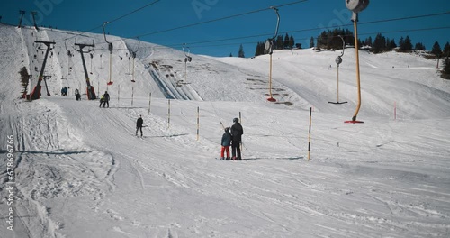 People skiing in alps mountains on sunny day - Skier riding down on winter time and taking ski lift for going up - Snow sport training and vacation concept  photo