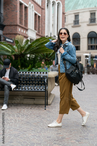 full length of beautiful young asian woman carrying bag walking on a city street after shopping on summer sale in center mall photo