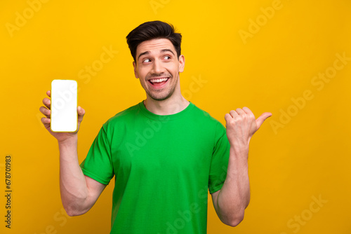 Photo of excited marketer guy wearing green t shirt point finger copyspace digital technologies update isolated on yellow color background