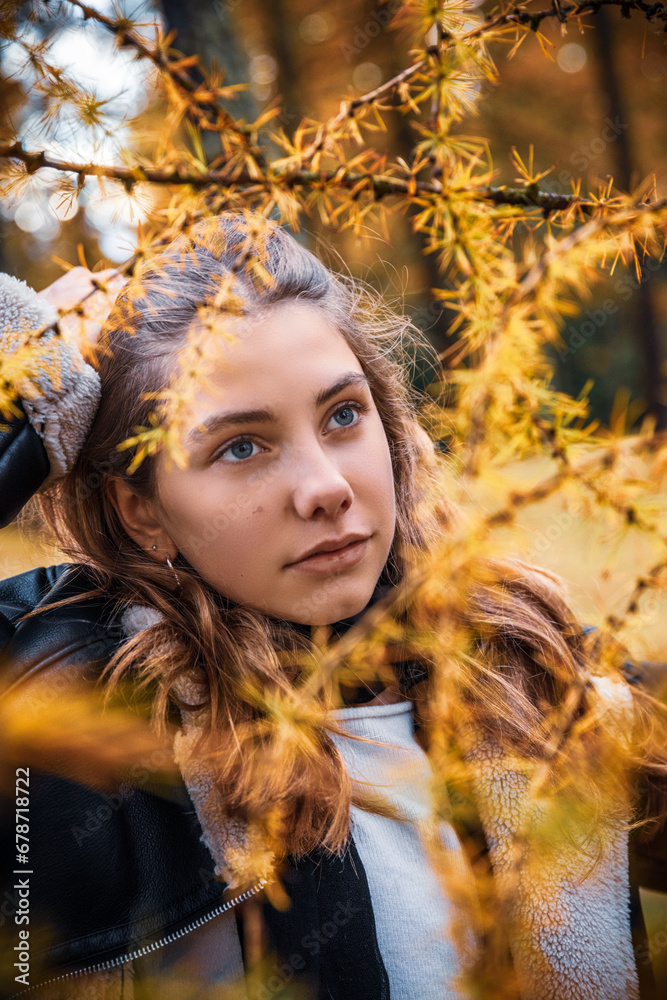 Portrait of teenage girl standing in yellow autumn larch trees in the forest. Portrait of teenage girl standing in yellow autumn larch trees in the forest.