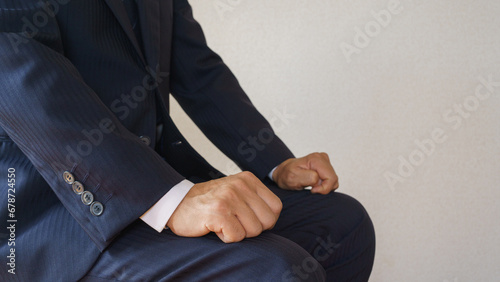 手をグーにして正しい姿勢で座るビジネスマン｜面接・商談などで待機するイメージ