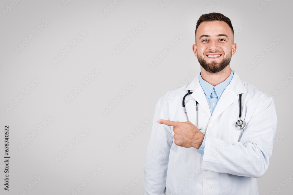 Smiling man doctor pointing left at free space, wearing white coat Smiling man doctor pointing left at free space, wearing white coat