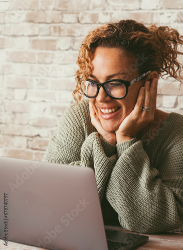 Cheerful attractive woman doing video call conference with computer connection. Home technology leisure and communication online. Female people smile at display at home. Modern lady use pc on the desk photo