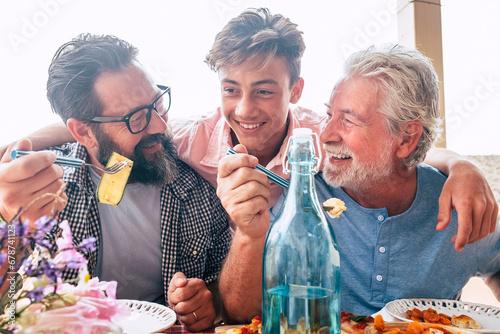 Father grandfather and son eaing together having fun. father's day concept celebration with men family enjoying meal on the table. Cheerful man young adult and mature laughing and having lunch photo