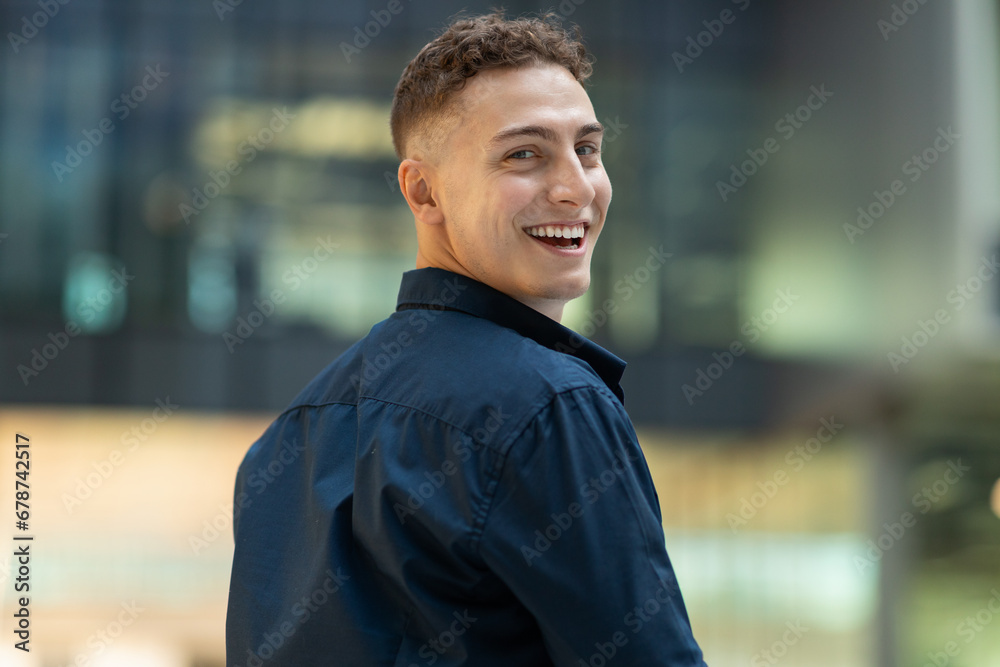 Fototapeta premium Positive surprised attractive millennial caucasian man student in casual look back in city, walk, outdoor