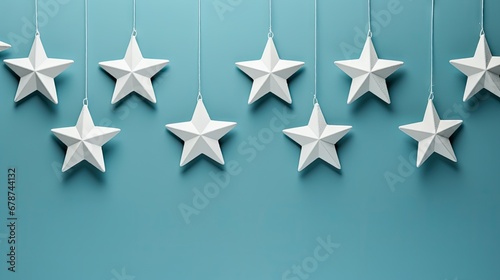  five white origami stars hanging from strings against a teal blue background with a string of white stars hanging from the end of each of each of the string.