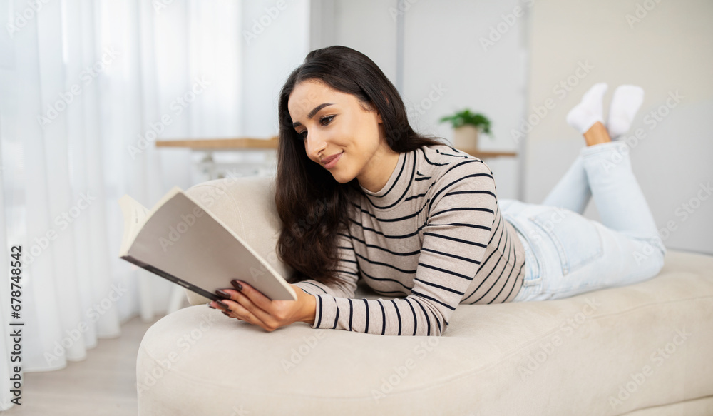 Happy calm young pretty arab woman read book, planning work, lie at sofa Happy calm young pretty arab woman read book, planning work, lie at sofa
