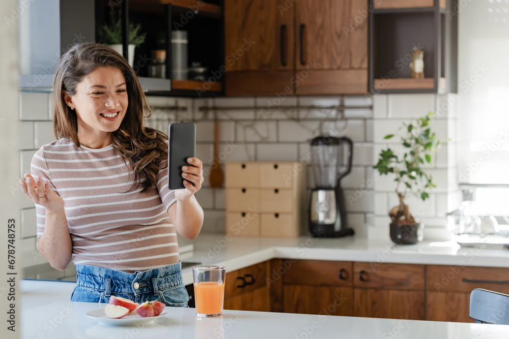 Young woman influencer vlogging over her smartphone in her modern home kitchen Young woman influencer vlogging over her smartphone in her modern home kitchen