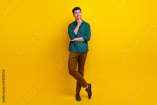 Full length photo of minded nice man wear trendy clothes look up empty space interesting offer banner isolated on yellow color background