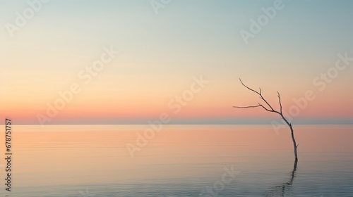  a lone tree in the middle of a body of water with a pink and blue sky in the background and a thin branch sticking out of the water in the foreground.