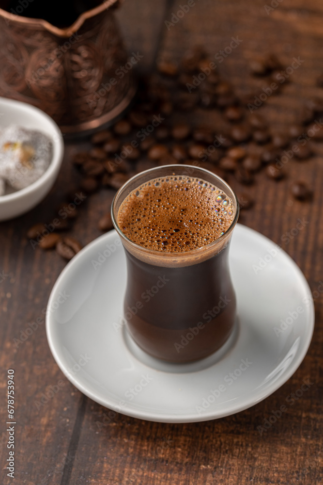 Turkish coffee in glass tea cup with Turkish delight on wooden table Turkish coffee in glass tea cup with Turkish delight on wooden table
