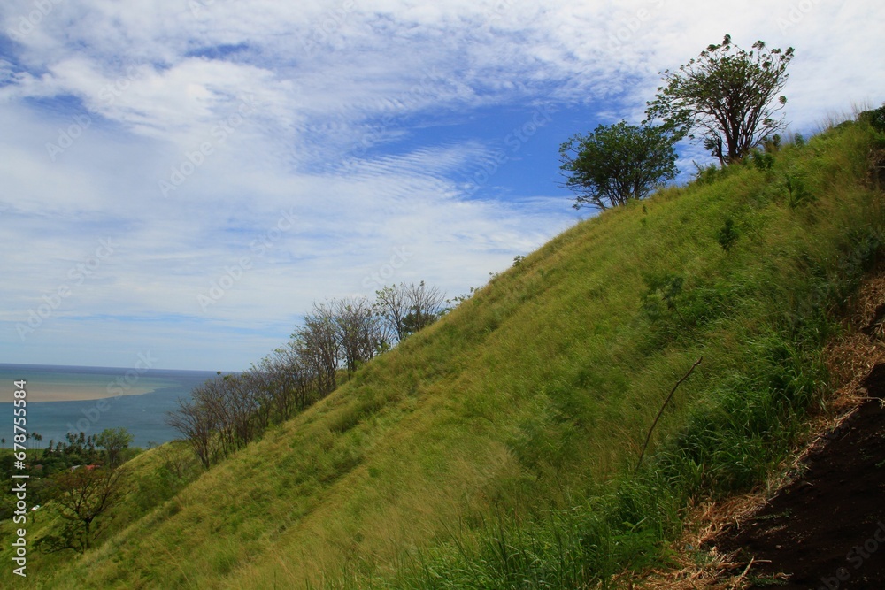Scenic shot of grass-covered green hills with clouds covering the blue sky