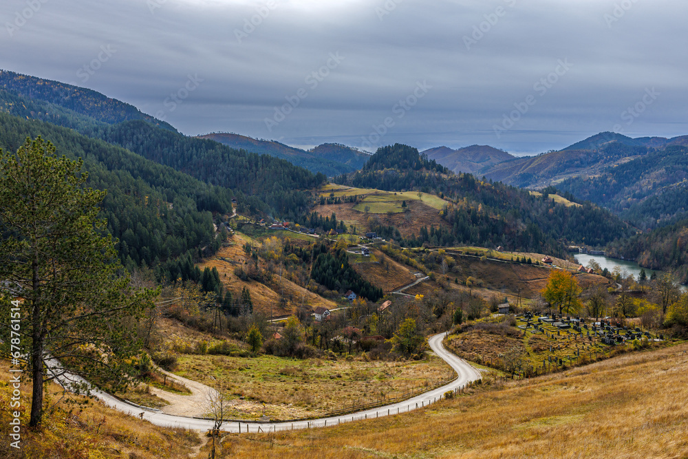 Fototapeta premium Mountain village in Serbia in bright autumn colors with Cemetery on the front