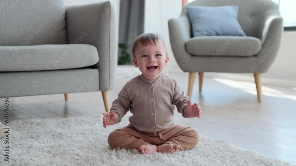 Cheerful little boy sits with a bright smile on face, eyes sparkling with happiness. With boundless energy, he repeatedly lifts off the ground, laughter filling the room as he jumps with pure joy. Cheerful little boy sits with a bright smile on face, eyes sparkling with happiness. With boundless energy, he repeatedly lifts off the ground, laughter filling the room as he jumps with pure joy.