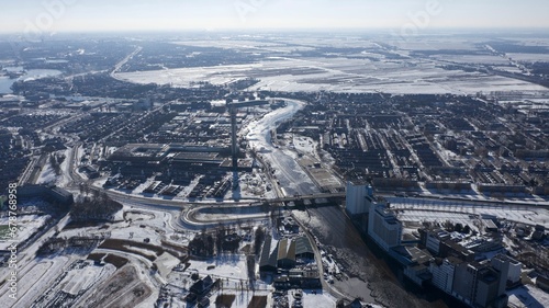 Aerial shot of a city, with a frozen river and snowy fields on a cloudy winter day