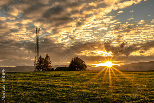 Krajobraz zachodzącego słońca, (nadajnik, słup, drzewa, chmury, niebo, rozbłysk, słońce, góry) © Piotr Gancarczyk