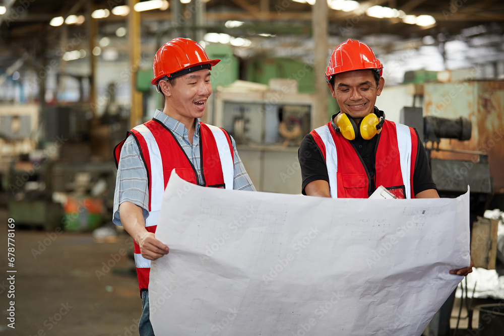 male factory workers holding paper and talking about works or project