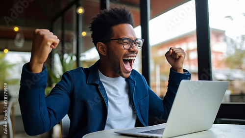 Ecstatic African American man celebrates online job success. photo