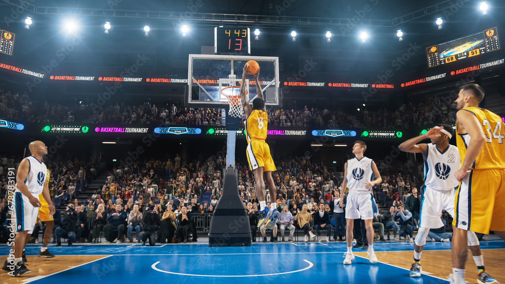 African American National Basketball Superstar Player Scoring a Powerful Slam Dunk Goal with Both Hands In Front Of Cheering Audience Of Fans. Cinematic Sports Shot with Back View Action. - obrazy, fototapety, plakaty 