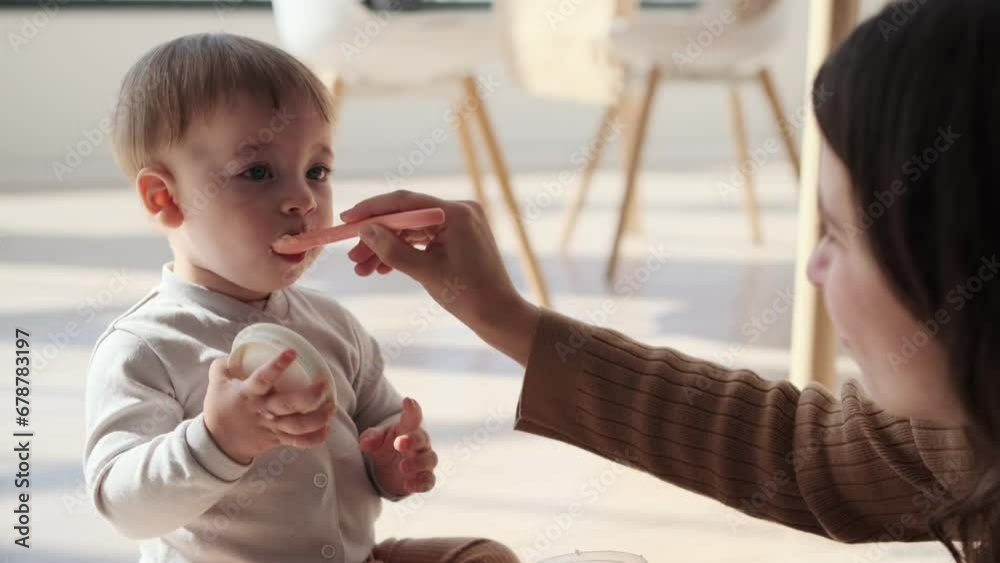 Devoted mother gently assists little son during mealtime. Eyes are filled with patience and encouragement, creating an atmosphere of support and love. Devoted mother gently assists little son during mealtime. Eyes are filled with patience and encouragement, creating an atmosphere of support and love.