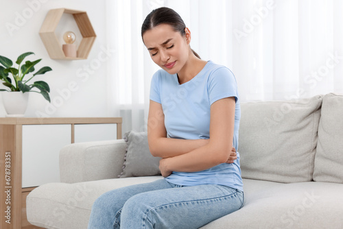 Woman suffering from abdominal pain on sofa at home. Unhealthy stomach