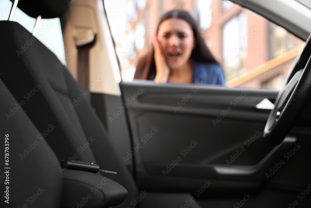 Automobile lockout, key forgotten inside, selective focus. Emotional woman looking through car window Automobile lockout, key forgotten inside, selective focus. Emotional woman looking through car window