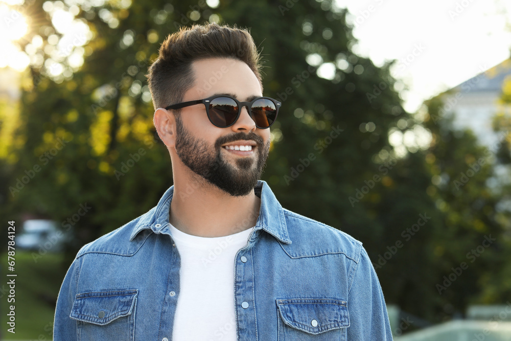 Handsome smiling man in sunglasses outdoors, space for text Handsome smiling man in sunglasses outdoors, space for text