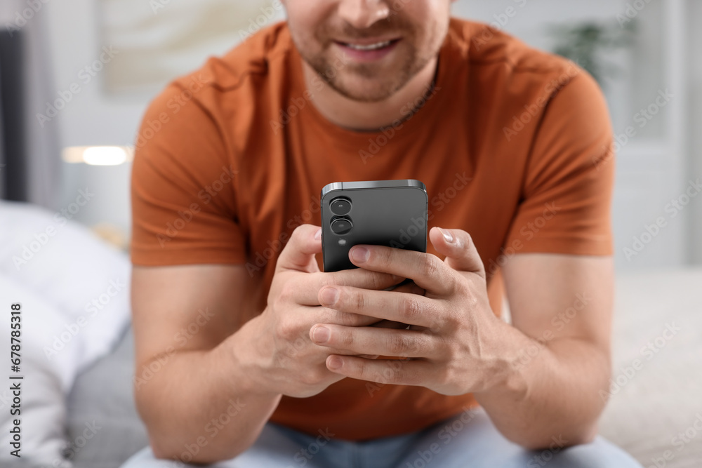 Man sending message via smartphone on bed at home, closeup Man sending message via smartphone on bed at home, closeup