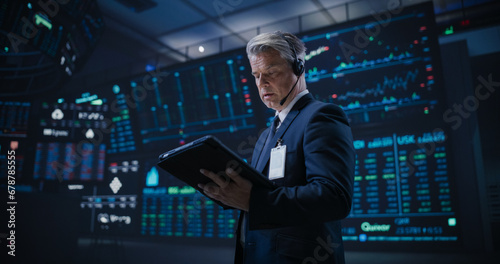 Low Angle Portrait of a Proactive Stock Exchange Manager Working in Modern Office. Adult Trader Communicating Orders with a Headset and Microphone, Talking on a Call with Auction Operators