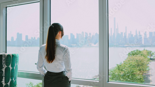 Portrait of cute cheerful professional Caucasian businesswoman in classy suit looking at window in modern company office. Elegant successful young woman looking at camera and smiling.