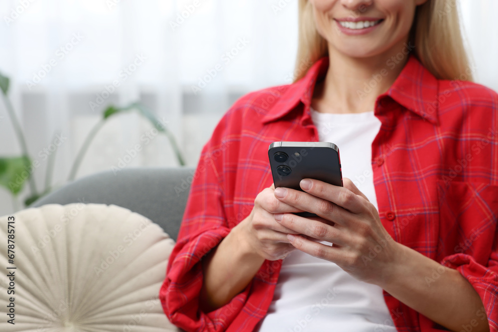 Woman sending message via smartphone at home, closeup Woman sending message via smartphone at home, closeup
