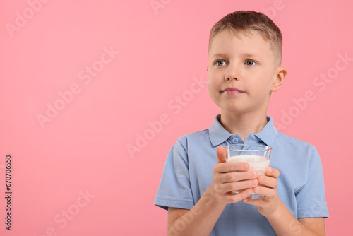Cute boy with glass of fresh milk on pink background, space for text