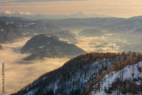 Winter landscape with snow covered mountains and clouds in the morning, Slovenia. View from Vogel to lake Bohinj in the fog.