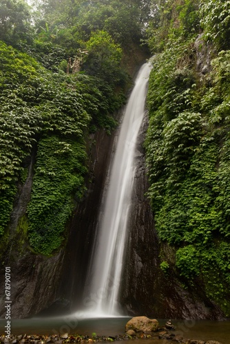 Vertical shot of a beautiful narrow waterfall in a forest
