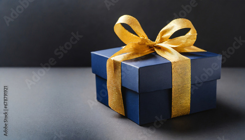 dark blue gift box with elegant gold ribbon on dark background greeting gift with copy space for christmas present holiday or birthday