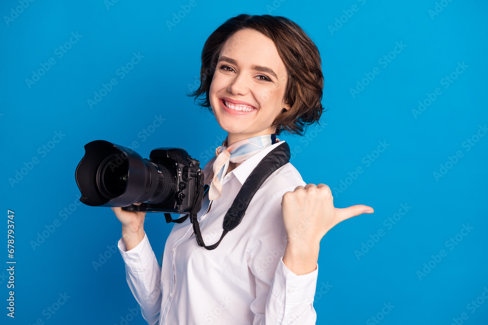 Profile portrait of cheerful pretty girl beaming smile indicate thumb empty space isolated on blue color background Profile portrait of cheerful pretty girl beaming smile indicate thumb empty space isolated on blue color background