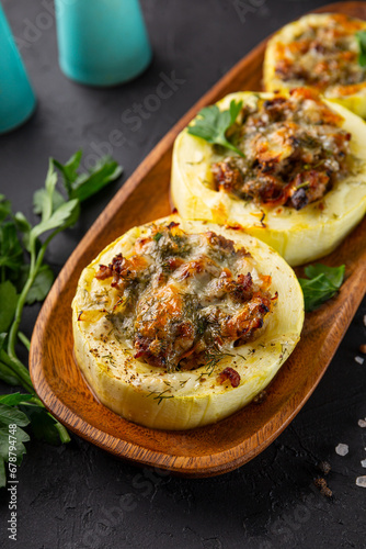 Round zucchini baked with minced meat and cheese on the black background vertical photo