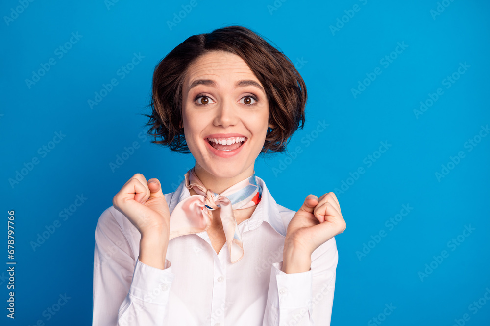 Photo of astonished positive girl raise fists open mouth shout yes celebrate isolated on blue color background Photo of astonished positive girl raise fists open mouth shout yes celebrate isolated on blue color background
