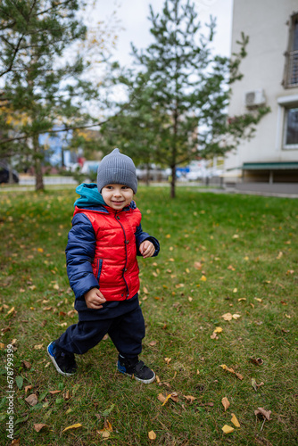 A Playful Young Boy in a Vibrant Jacket and Hat. A young boy in a red and blue jacket and hat photo