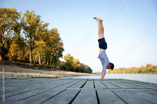 Mid aged man practicing yoga pose handstand outdoor