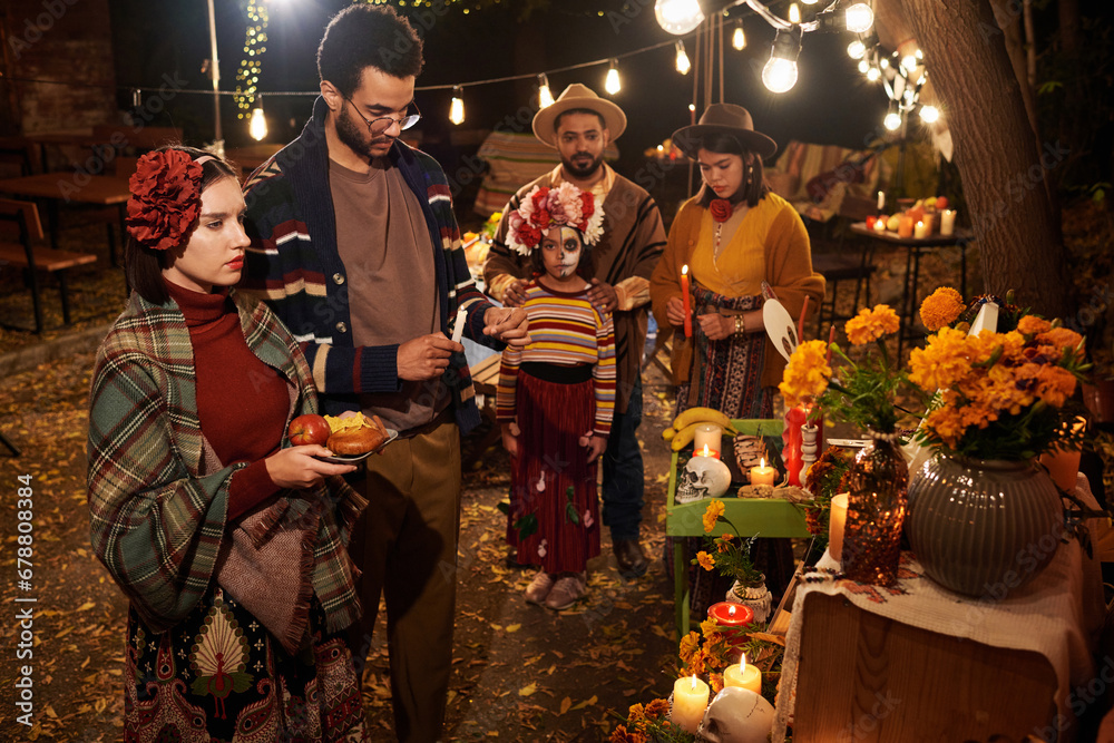 Obraz premium Big family in traditional clothes remembering their dead relatives standing at altar outdoors