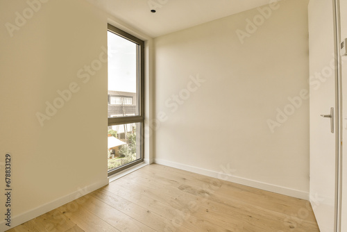 an empty room with wood floor and large window looking out onto the street below, there is a white door that leads to a © Casa imágenes