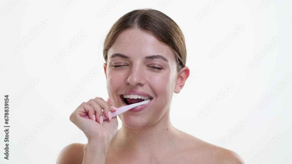Caucasian woman cleans teeth with a radiant smile, showcasing the importance of oral hygiene with enthusiasm. Against a white backdrop, happiness adds a touch of positivity to the dental care. Caucasian woman cleans teeth with a radiant smile, showcasing the importance of oral hygiene with enthusiasm. Against a white backdrop, happiness adds a touch of positivity to the dental care.