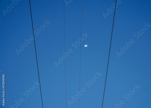 View of the sky and a bright moon intercepted with cables