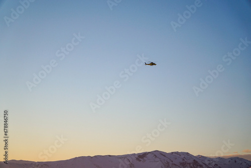 Helicopter flying over the Andes mountain range during the sunset.