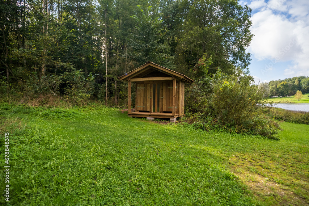 Wooden toilet in the countryside with a heart-shaped hole on the door. Wooden toilet on a background of trees.