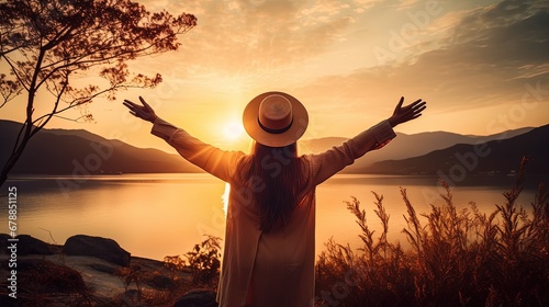 woman posing with her back facing mountains on sunset in nature with open hands. silhouette summer landscape. Freedom Concept